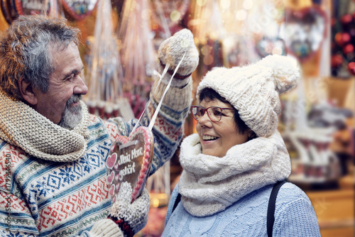 Senior couple on an outdoor Christmas market with gingerbread heart