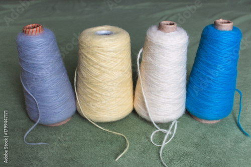 Variety colours of alpaca wool and silk. Cones of multicoloured yarn. Wool threads in a row. Row of blue, white, yellow and grey wool. Knitting hobby. Bobbins of yarn. Bright wool for knitting. 