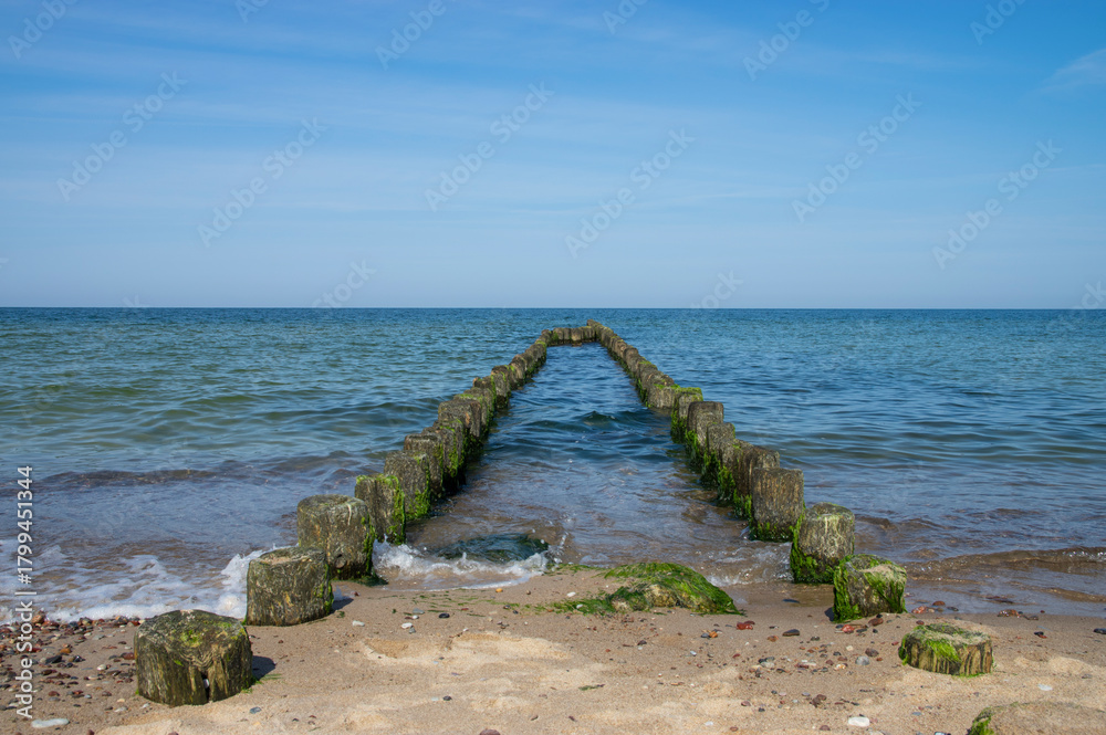 Fototapeta premium Drewniany falochron na spokojnym wybrzeżu morza Bałtyckiego