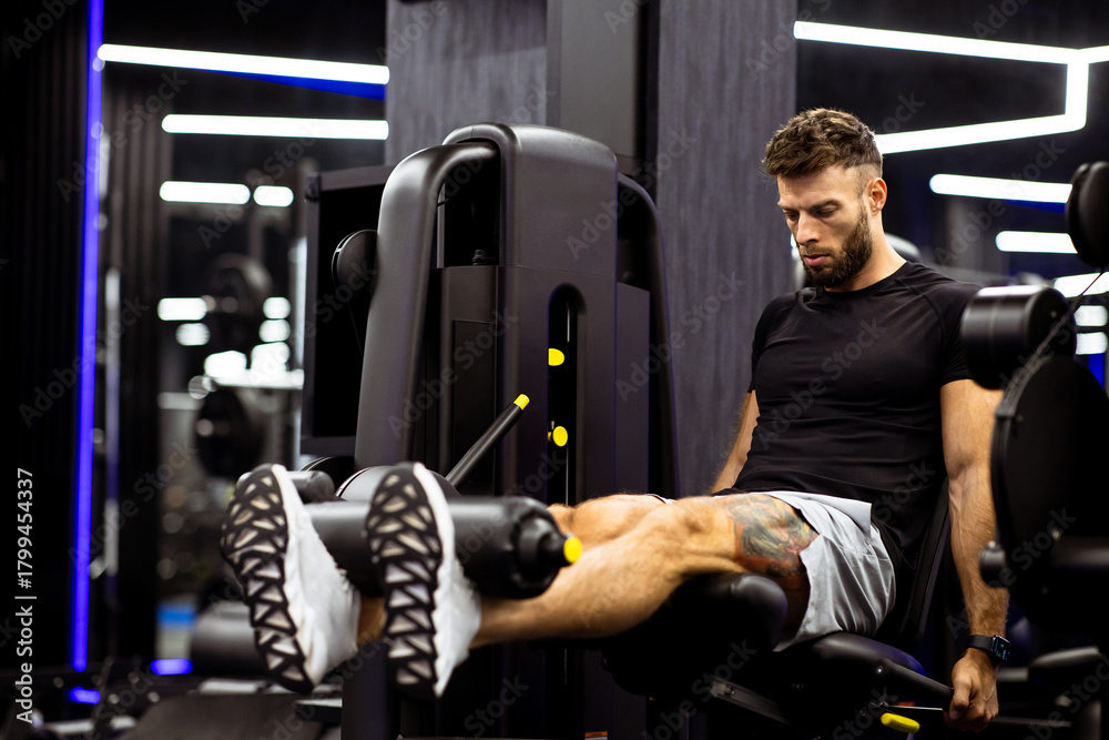 Naklejka premium Leg extension workout at gym during evening session for muscle growth and strength