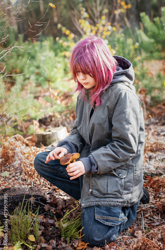 Teenager finding mushrooms in autumn forest outdoors