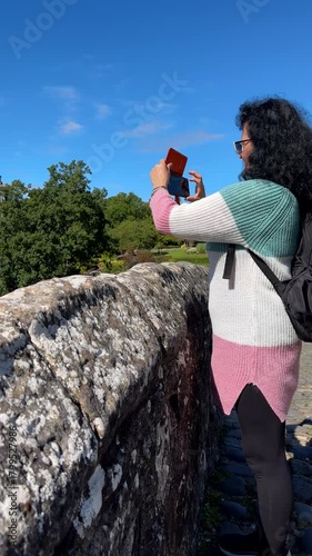 Vertical shot. Woman with long dark curly hair taking pictures of outstanding view in Ayr town, southwest coast Scotland.