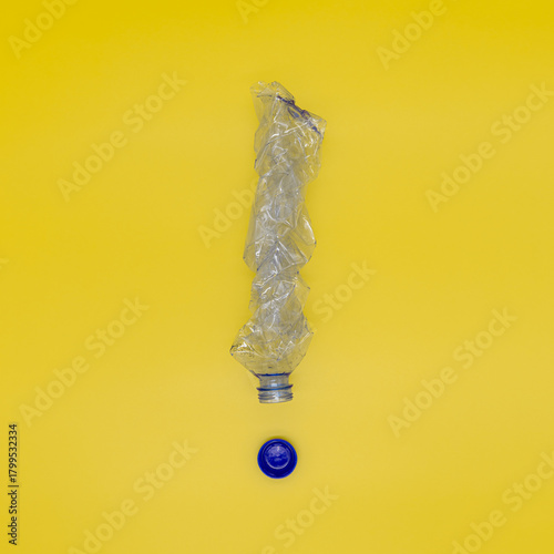 Squeezed plastic bottle in the form of an exclamation mark, the concept of preventing the planet from being polluted with garbage and plastic