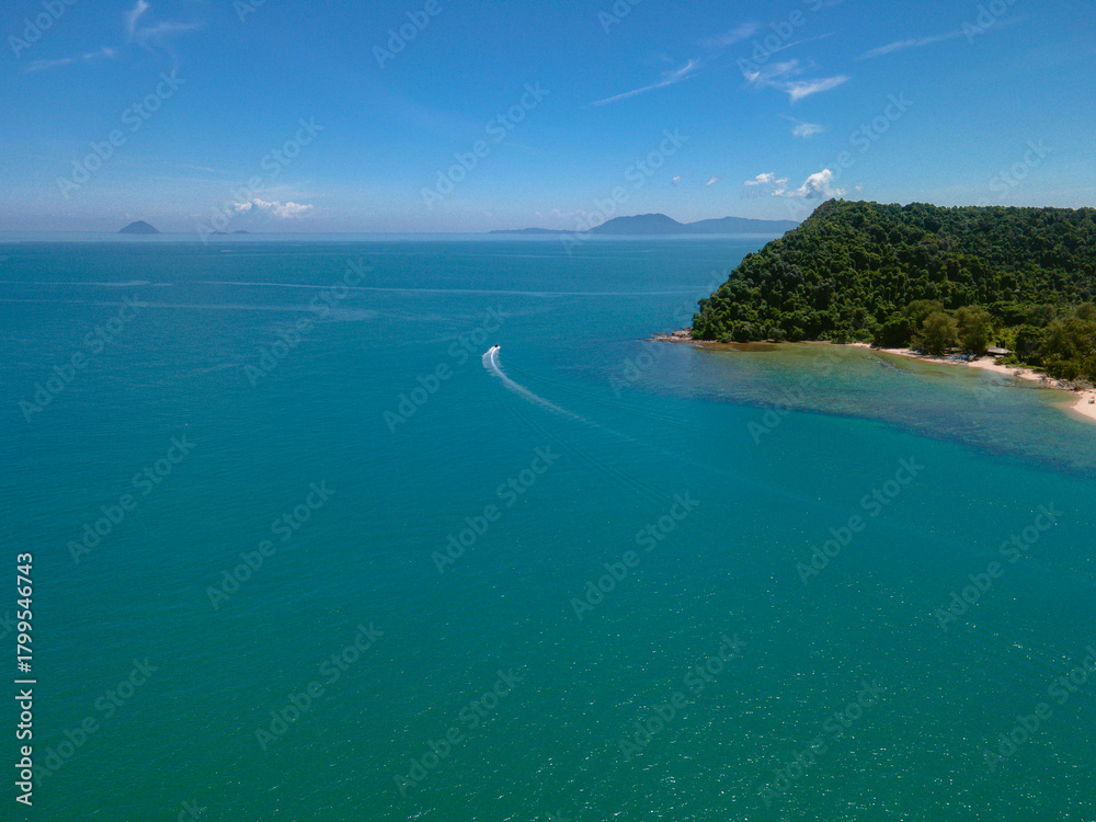 Fototapeta premium Aerial view of a small tropical island located just off the coast of Pantai Bukit Keluang in Besut, Terengganu. The island is covered in dense green forest and surrounded by vibrant turquoise waters.