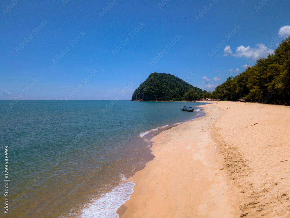 Obraz premium Aerial view of Pantai Bukit Keluang, Besut, Terengganu, showing turquoise waters, coastal cliffs, and clear sunny skies along the scenic shoreline.