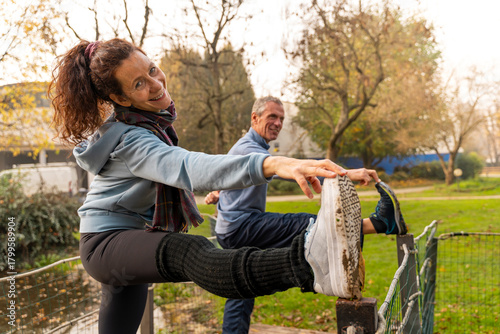 Senior couple enjoying their fitness routine, smiling and stretching body in green park