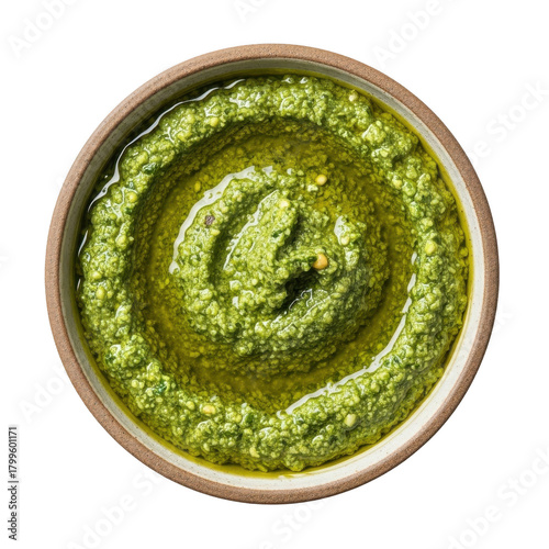 Overhead view of a rustic bowl filled with vibrant green basil pesto drizzled with olive oil against a stark