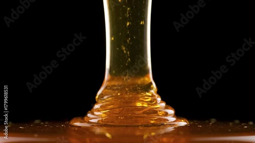 Close-up shot of golden honey pouring down against a dark background, showcasing its texture.