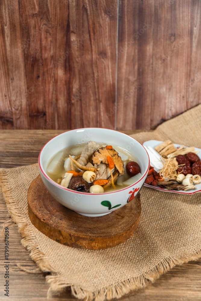 Fototapeta premium Flavorful Herbal Soup: A steaming bowl of nourishing herbal soup, rich with medicinal ingredients and a hint of jujube sweetness, served on a rustic wooden surface, promising warmth and well-being.