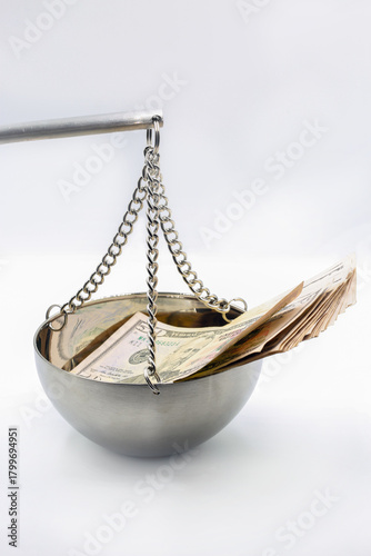 Financial balance concept with dollar bills on hanging scale closeup.