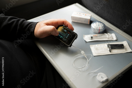 Checking insulin pump screen and preparing diabetes supplies while traveling by train
