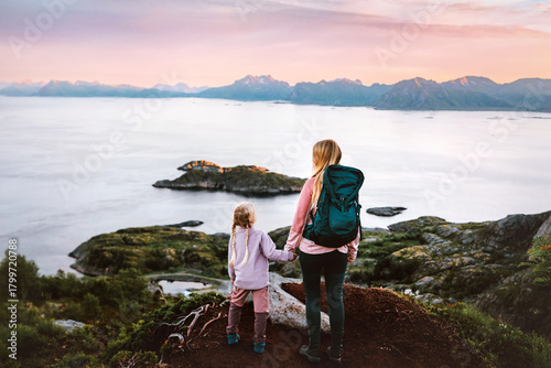 Mother and daughter holding hands hiking in Norway family active vacations  - parent mom and kid enjoying sea and mountains aerial view in Lofoten Islands summer tour together camping adventure trip