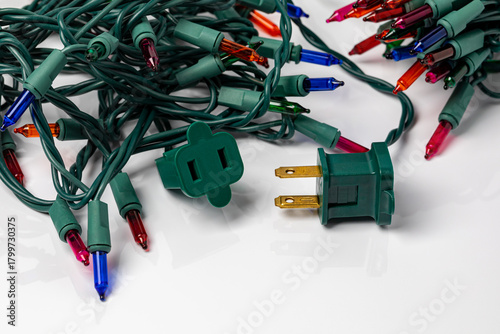Mini Christmas string lights outlet plug isolated on white background. Holiday decoration safety, inspection and lighting concept.