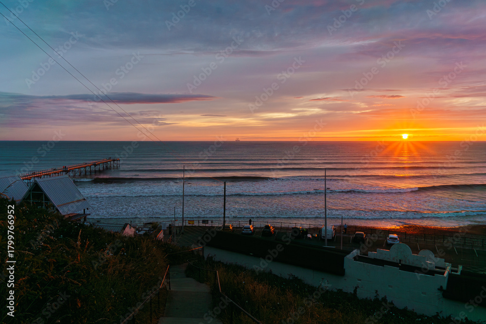 Fototapeta premium Sunset Over Saltburn Pier — Warm Glow, Pathway Descent, and Coastal Stillness in Saltburn-by-the-Sea