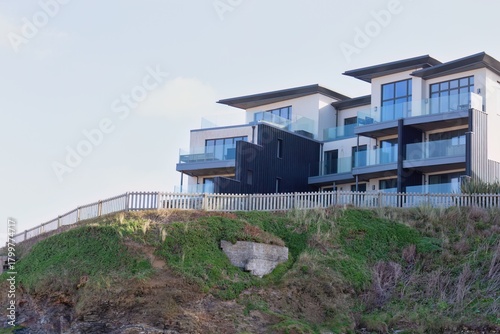 Luxury seaside condos sit atop a green cliff. The modern architecture offers scenic coastal views
