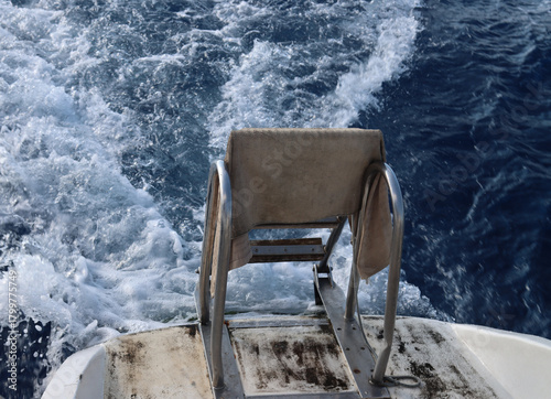 Boat stern creating wake on deep blue ocean water