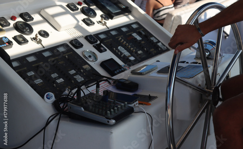 Hand holding steering wheel on boat dashboard
