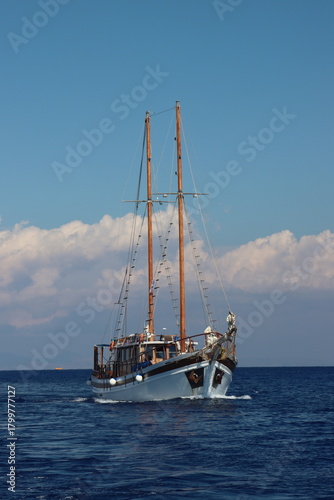 Classic sailboat navigating blue ocean under clear sky