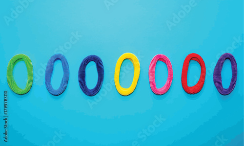 A line of multi-colored plasticine rings or zeros on a bright blue background, abstract design element