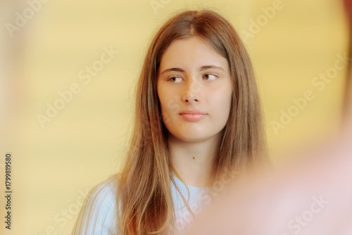 Cuadro en lienzo A young woman with long brown hair, dressed in a light blue dress and heart pendant, looks thoughtfully ahead during a formal indoor event