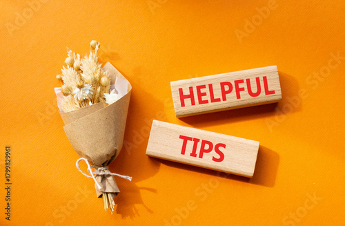 Helpful tips symbol. Wooden blocks with words Helpful tips. Beautiful orange background with bouquet of flowers. Business and Helpful tips concept. Copy space.