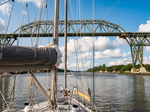 Sailboat approaching Hochdonn High Bridge on Kiel Canal in Schleswig-Holstein Germany