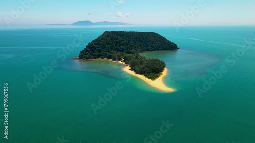 Aerial view of a small tropical island located just off the coast of Pantai Bukit Keluang in Besut, Terengganu. The island is covered in dense green forest and surrounded by vibrant turquoise waters.