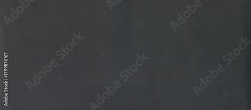Black rough surface of old paper or cardboard, background, texture. Backdrop of black paper surface with elements of aging. Old and shabby paper piece. Ancient wall in ashen color. Black paper surface