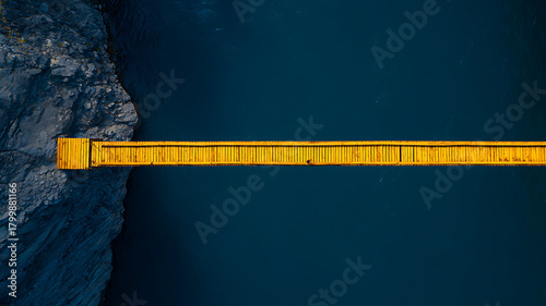Aerial View of a Bright Yellow Pedestrian Bridge Over Dark Blue Water