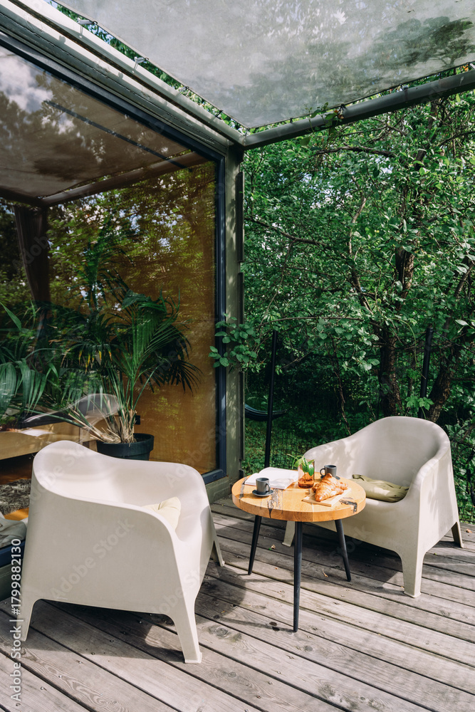 Fototapeta premium Cozy outdoor seating area with modern chairs surrounded by greenery