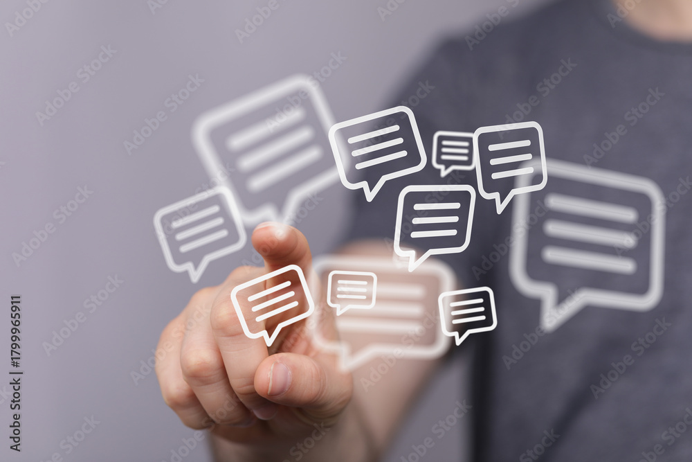 Fototapeta premium Close-up of hand touching speech bubble icons. Illustrating communication, social media, and digital messaging. Concept of online interaction.