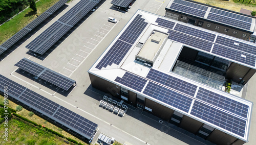 Fototapeta Naklejka Na Ścianę i Meble -  Aerial view of building with solar panels on a roof and parking space with solar canopies