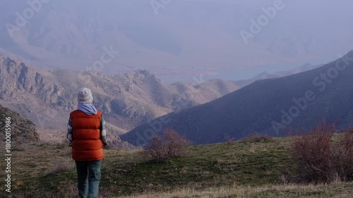 A lonely traveler walks with his dog in the mountains above the Ili River, enjoying the tranquility of nature and the mountain landscape.