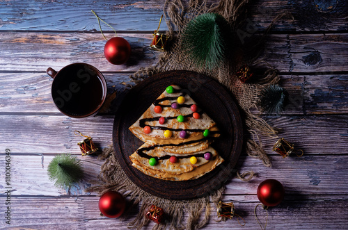 Fried crepes with peanut butter filling and chocolate and multicolored candies topping in the form of Christmas tree