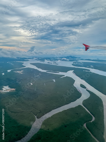 Breathtaking aerial perspective from an airplane window captures intricate network of rivers winding through vast mangrove forest, showcasing stunning natural coastline of Krabi, Thailand