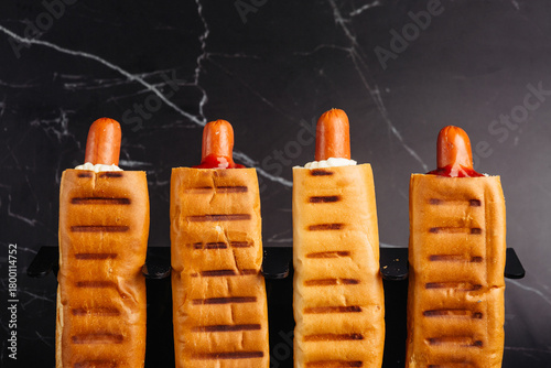 French hot dogs in a sriracha bun look tempting against a dark background