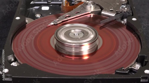 Open hard drive with red coloured platter, close-up view, starting rotation and platter UN-coloring