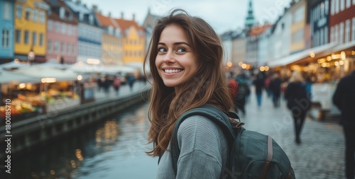 Young Woman Smiles by the Waterfront in Colorful City During Cloudy Afternoon