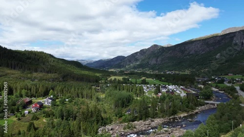 Drone flying over Norway, capturing mountains, scattered houses, winding roads, and a scenic natural landscape from above in a peaceful rural setting.