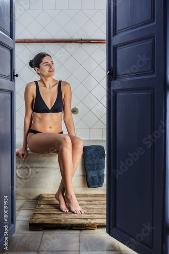 Woman relaxing in a thermal bath at a spa surrounded by tranquil decor