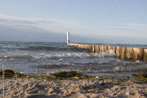 Stimmungsvolle Küstenaufnahme vom Ostseestrand bei Heiligenhafen: Sand, Seegras und eine hölzerne Buhne mit Seezeichen  