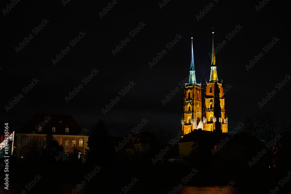 Fototapeta premium View of illuminated Wroclaw Cathedral and Church of the Holy Cross reflected in the Odra River at night. Concept of architecture, travel and religion