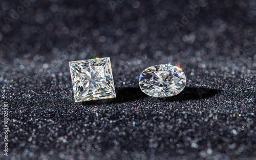 Two diamond shaped gems are on a black surface