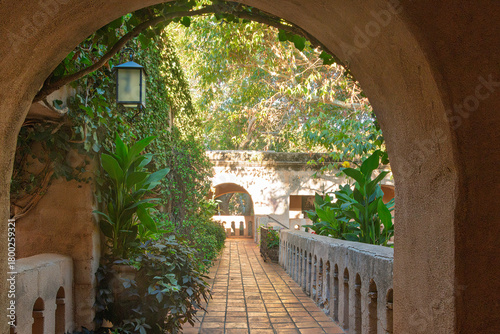 A stone walkway through an arched opening leads to shops and art galleries on the 2nd floor of Mexican-styled Talapuepapue Arts Village, Sedona, Arizona, USA.

