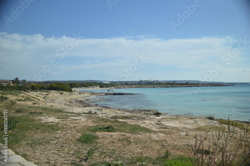 Scenic coastal view with rocky shore and clear blue water under a bright sky, tranquil nature landscape, copy space