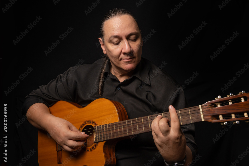 Obraz premium Portrait of a young Brazilian gentleman with a guitar, portrait of a middle-aged man from Brazil, black background, selective focus.