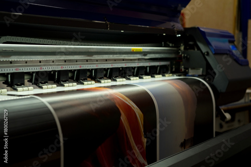 Large format inkjet printer printing colorful graphic on vinyl material in commercial print shop