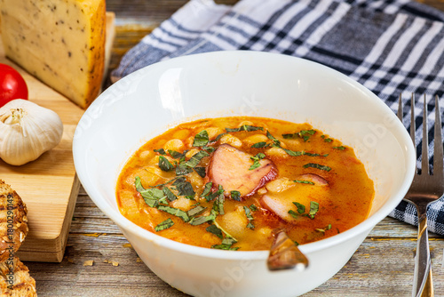 A hearty bowl of cooked bean stew with tender pieces of meat, served in a clean white dish. The warm, rich broth highlights the soft beans and juicy meat, while natural lighting 