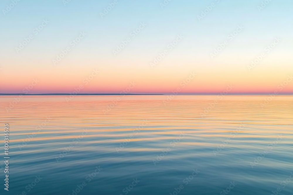 Fototapeta premium Evening sky glows with warm hues during sunset over calm water surface