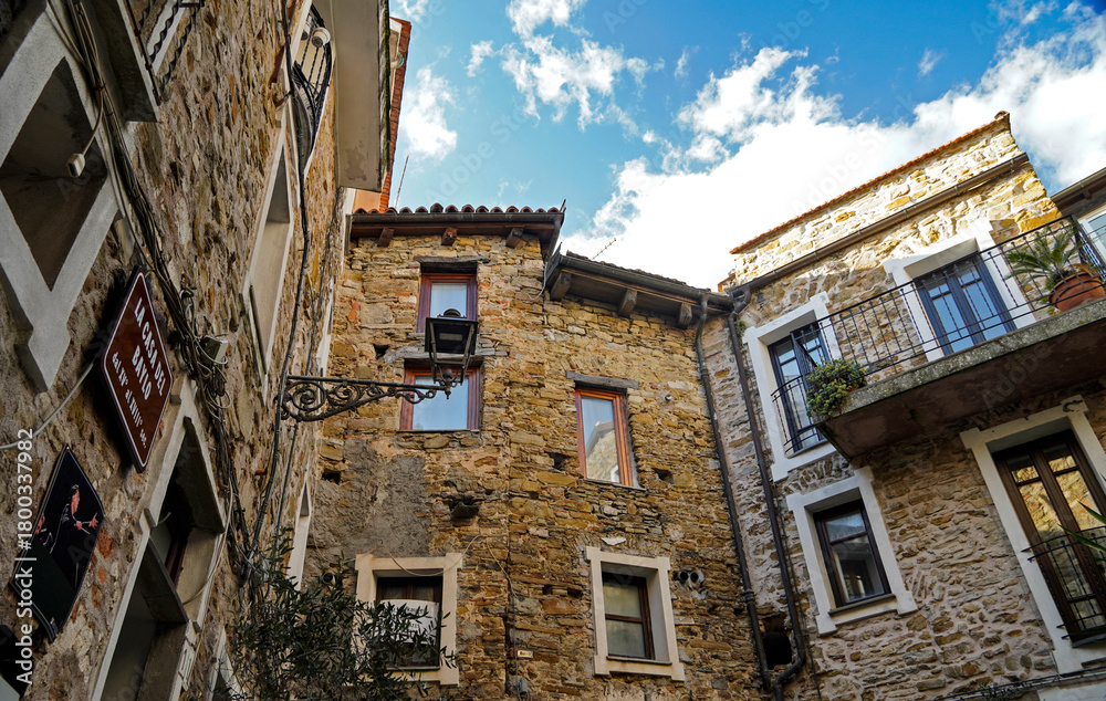 Fototapeta premium Windows of 15th century buildings in the he hilltop town of Perinaldo, Italy reflect the blue sky above the mountain village that draws thousands of tourists to see its medieval setting.